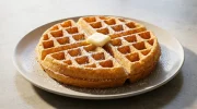 Gaufres de Bruxelles dorées et croustillantes saupoudrées de sucre glace sur une assiette.